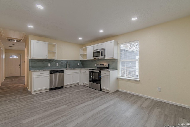 kitchen featuring backsplash, appliances with stainless steel finishes, open shelves, white cabinetry, and light wood-style flooring