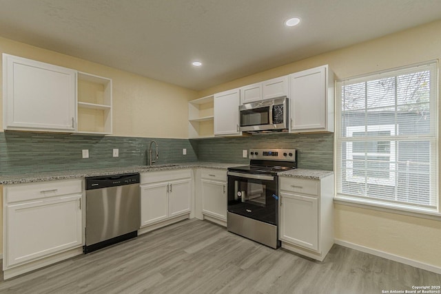 kitchen featuring open shelves, appliances with stainless steel finishes, a sink, light wood-style flooring, and white cabinetry