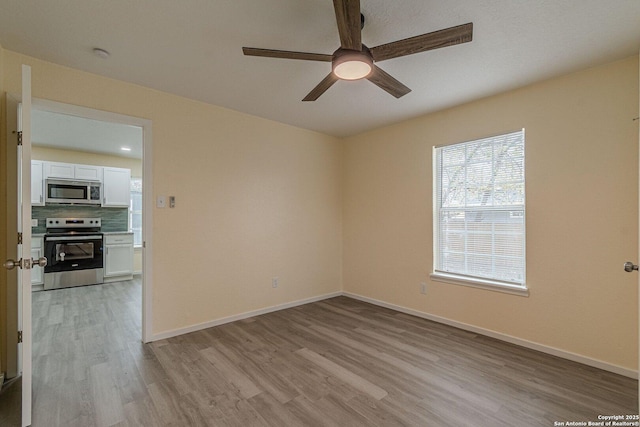 empty room with a ceiling fan, baseboards, and light wood-style flooring