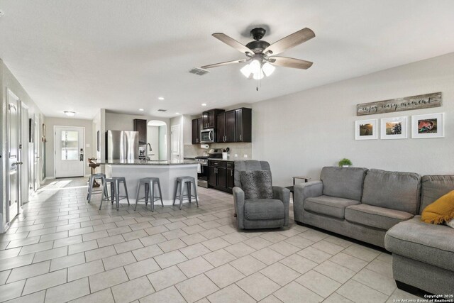 living room featuring arched walkways, ceiling fan, and visible vents
