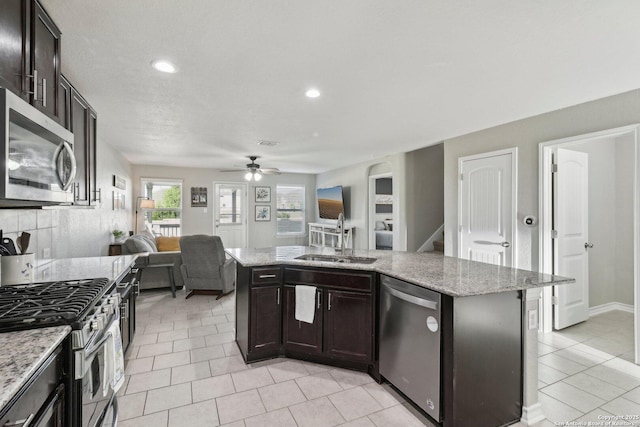 kitchen featuring ceiling fan, a sink, stainless steel appliances, open floor plan, and recessed lighting