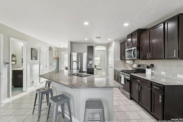 kitchen featuring visible vents, arched walkways, a sink, stainless steel appliances, and light tile patterned flooring