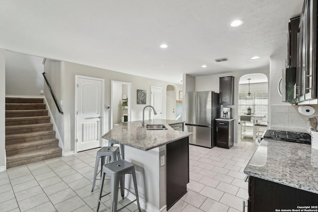 kitchen featuring visible vents, arched walkways, appliances with stainless steel finishes, a sink, and light tile patterned floors