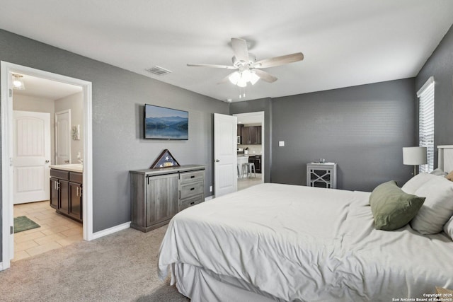 bedroom featuring ceiling fan, light colored carpet, ensuite bath, baseboards, and visible vents