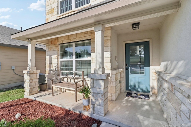 doorway to property featuring a porch, stucco siding, stone siding, and cooling unit