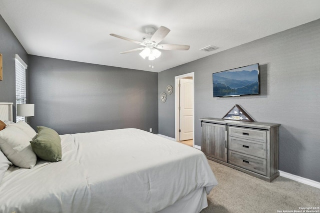 bedroom with visible vents, a ceiling fan, baseboards, and light colored carpet