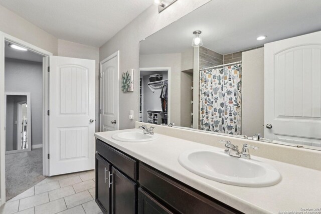 bathroom with tile patterned flooring, a sink, curtained shower, and double vanity