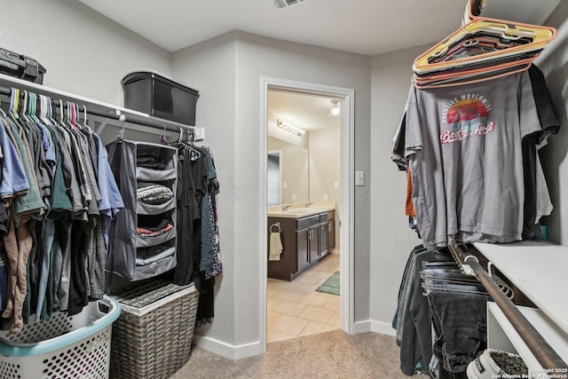walk in closet with light colored carpet, a sink, light tile patterned floors, and visible vents