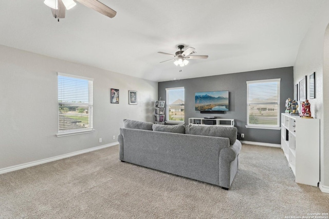 carpeted living area with baseboards and a ceiling fan