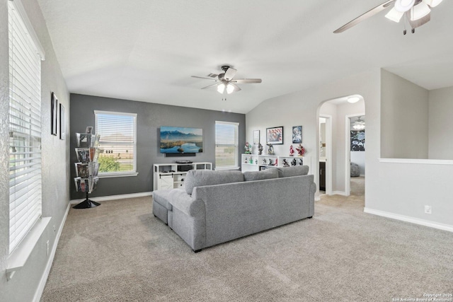 carpeted living room featuring baseboards, a ceiling fan, arched walkways, and vaulted ceiling