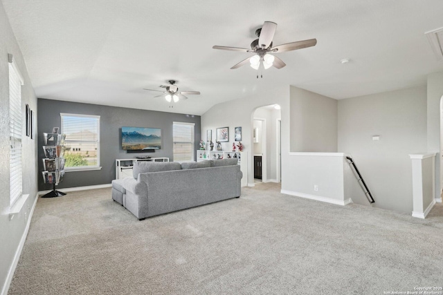 living area with arched walkways, a ceiling fan, and carpet flooring