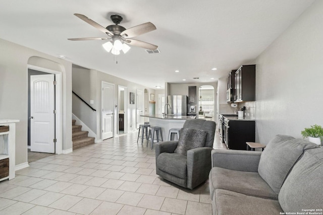 living room with light tile patterned flooring, arched walkways, a ceiling fan, recessed lighting, and stairway