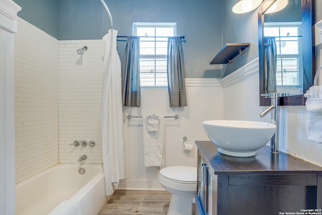 bathroom featuring vanity, wainscoting, wood finished floors, toilet, and shower / bath combo