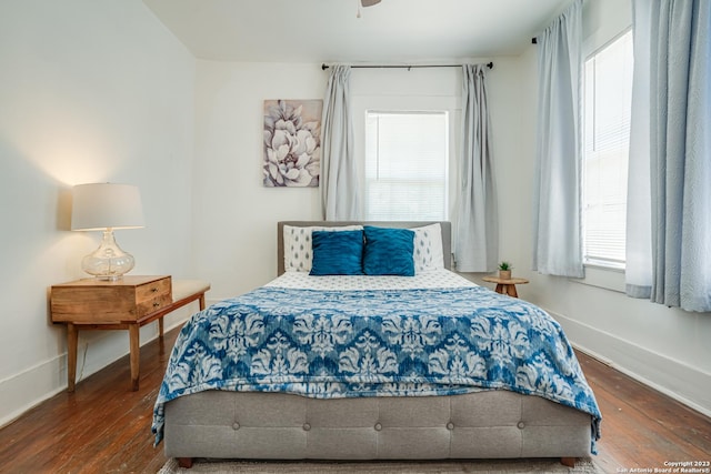 bedroom with baseboards, multiple windows, and hardwood / wood-style floors