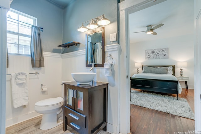 full bathroom with connected bathroom, ceiling fan, wainscoting, toilet, and wood finished floors