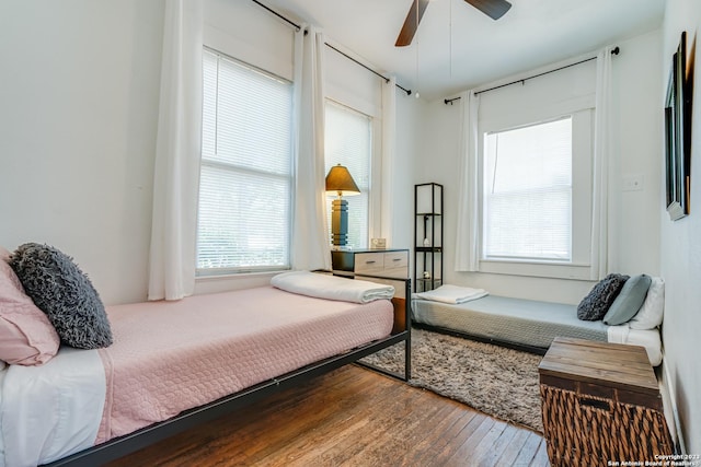 bedroom featuring wood-type flooring, a ceiling fan, and multiple windows