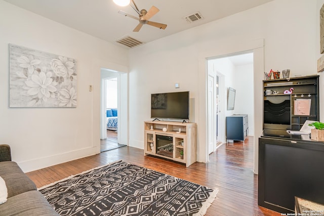 living room featuring visible vents, a ceiling fan, baseboards, and hardwood / wood-style floors
