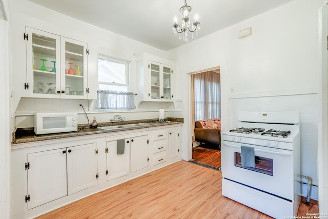 kitchen with a sink, light wood finished floors, white cabinets, and white appliances