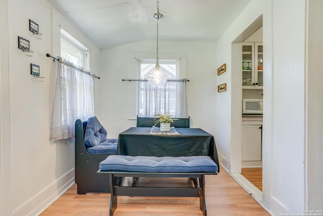 dining area with baseboards, wood finished floors, vaulted ceiling, and a healthy amount of sunlight