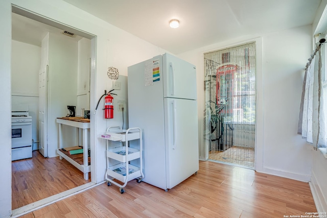 kitchen featuring white appliances, baseboards, visible vents, and light wood-style floors