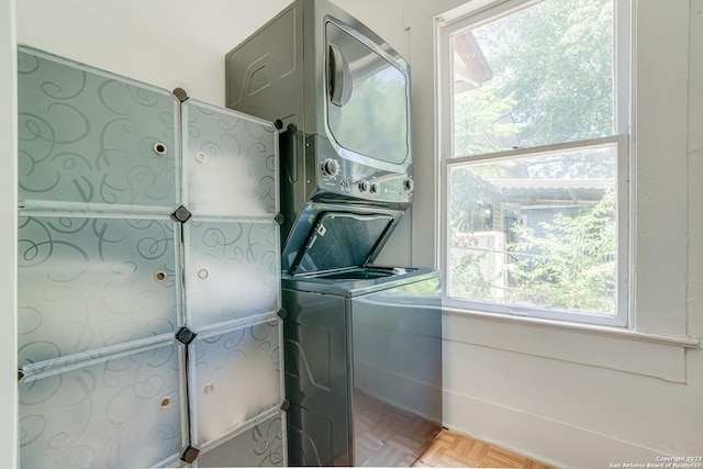laundry area with laundry area, a healthy amount of sunlight, and stacked washer and clothes dryer