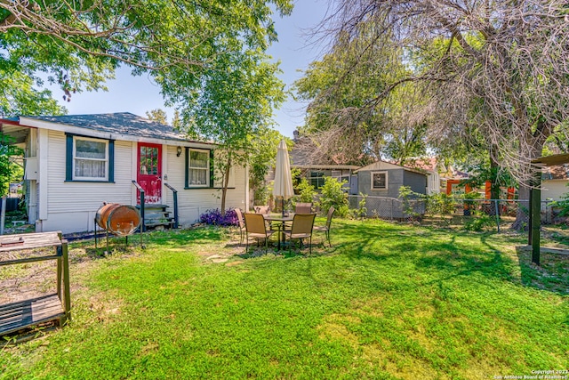 rear view of property featuring fence and a yard