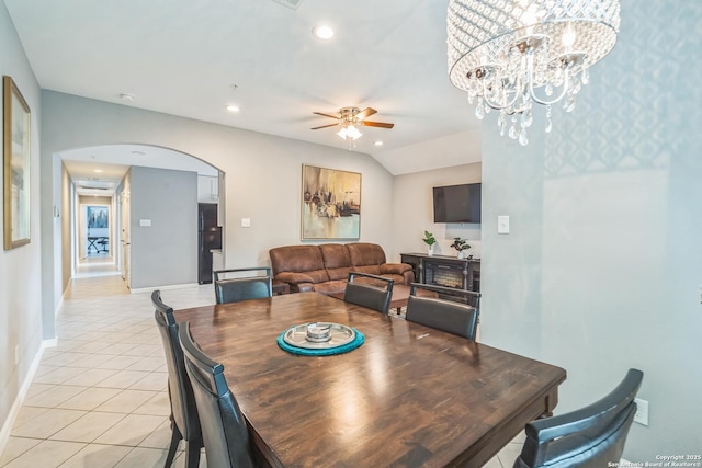 dining room with light tile patterned flooring, arched walkways, ceiling fan with notable chandelier, recessed lighting, and baseboards