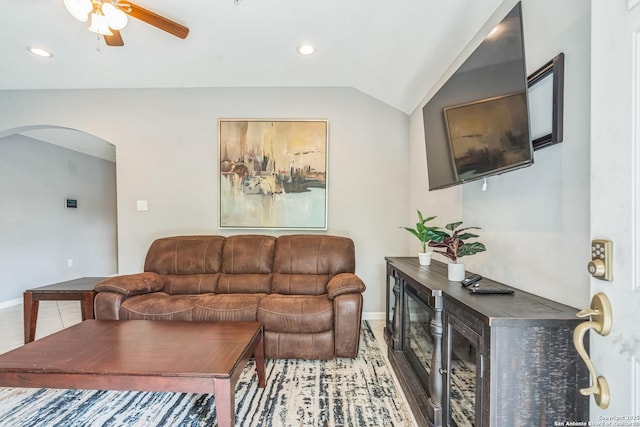 living room with a ceiling fan, baseboards, vaulted ceiling, and arched walkways