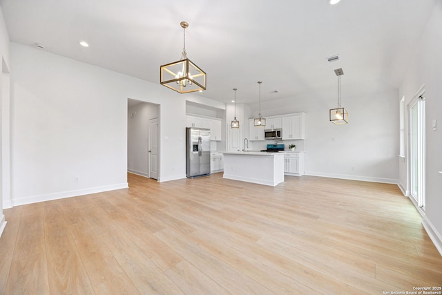 25 Main, Hempstead, TX 77445 - unfurnished living room featuring visible vents, a sink, light wood-style flooring, and a chandelier