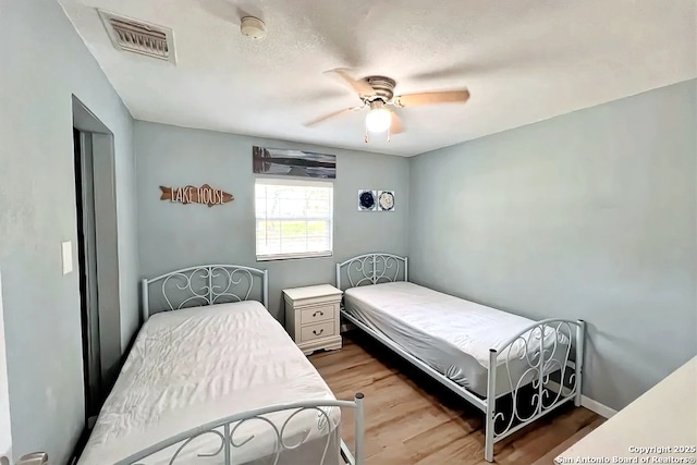 bedroom featuring ceiling fan, wood finished floors, and visible vents