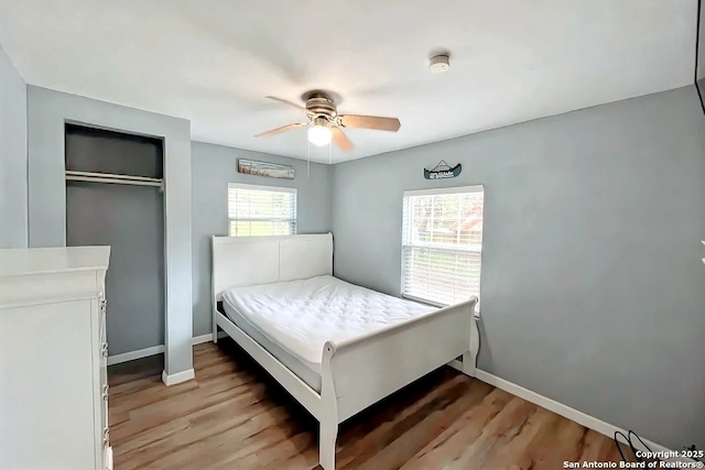 bedroom with baseboards, light wood finished floors, and multiple windows