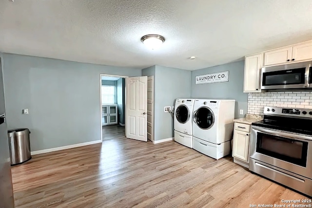 clothes washing area featuring washing machine and clothes dryer, laundry area, baseboards, and light wood-style floors