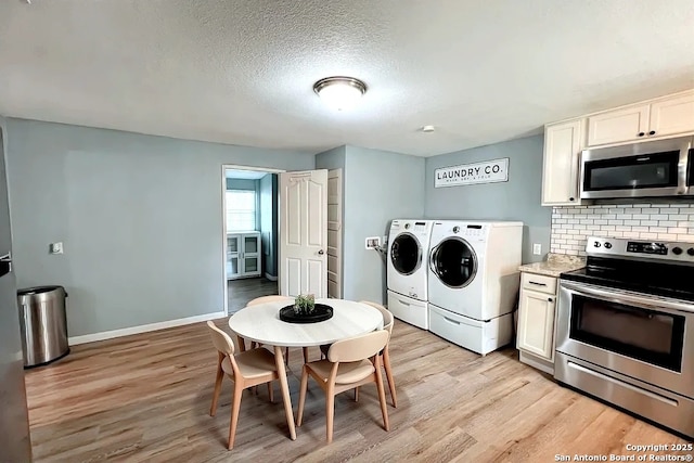 kitchen featuring washer and dryer, baseboards, tasteful backsplash, light wood finished floors, and stainless steel appliances