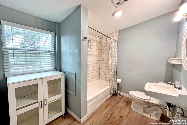 full bathroom featuring visible vents, shower / bath combo with shower curtain, wood finished floors, toilet, and baseboards