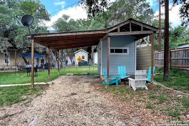 view of shed with dirt driveway and fence