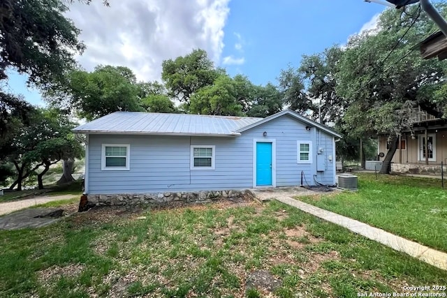 view of front of home with central AC, metal roof, and a front yard