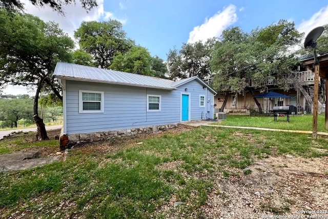 back of property featuring a lawn, metal roof, and central air condition unit