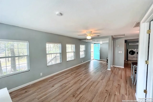 unfurnished living room featuring ceiling fan, light wood-style flooring, independent washer and dryer, and a wealth of natural light