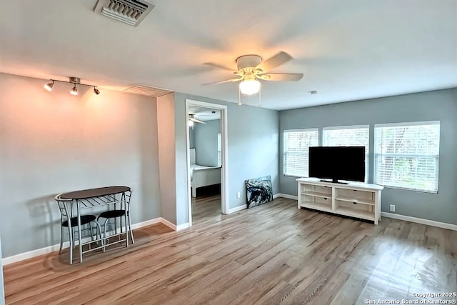 living area with visible vents, a ceiling fan, baseboards, and wood finished floors