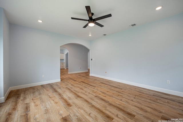 unfurnished room with arched walkways, ceiling fan, light wood finished floors, and visible vents