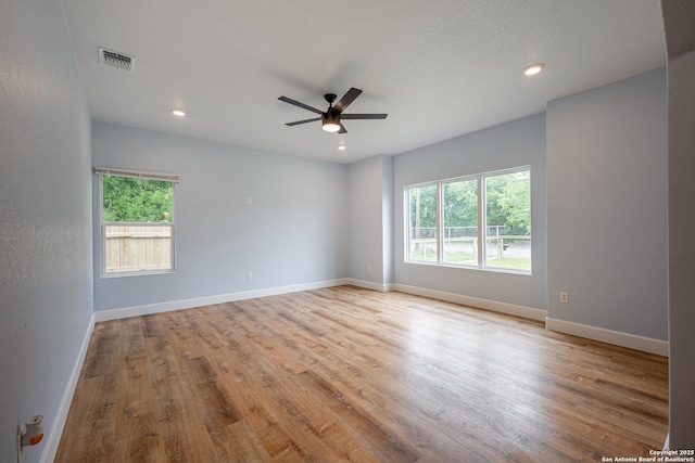 empty room with baseboards, plenty of natural light, a ceiling fan, and visible vents