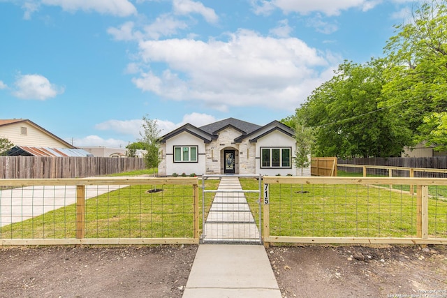 view of front of property with a fenced front yard, stone siding, stucco siding, a front yard, and a gate