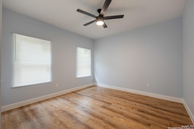 spare room featuring baseboards, a ceiling fan, and light wood finished floors