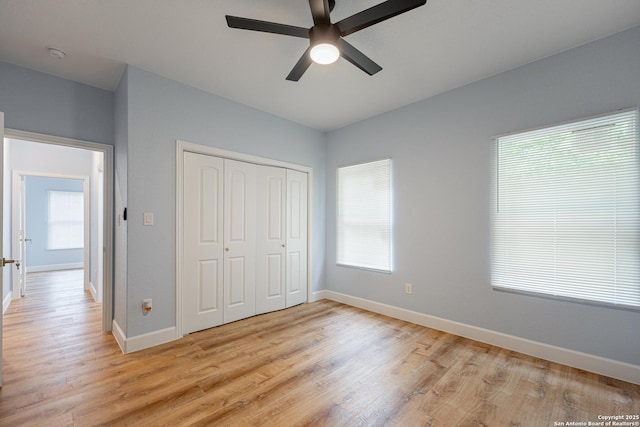 unfurnished bedroom featuring baseboards, light wood finished floors, ceiling fan, and a closet