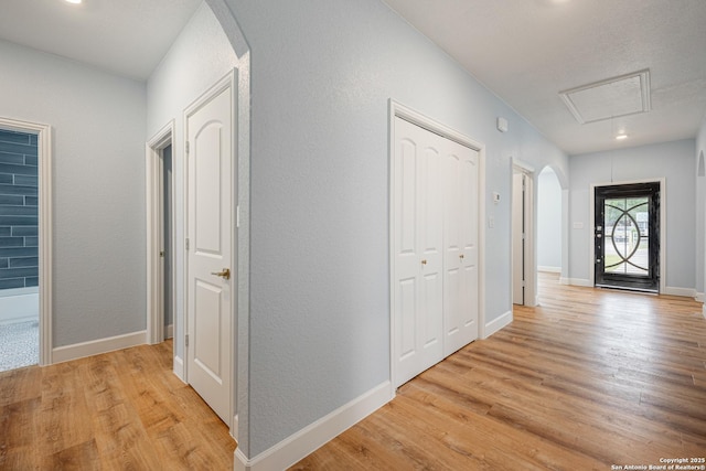 hall with attic access, arched walkways, baseboards, light wood finished floors, and recessed lighting