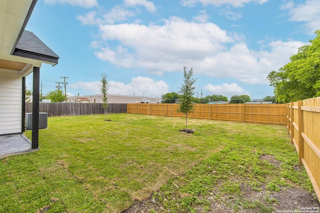 view of yard with a fenced backyard and central AC