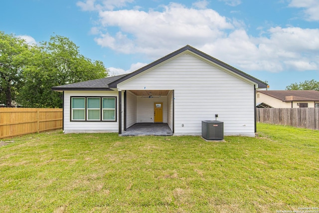 rear view of property featuring a lawn, central AC, a fenced backyard, and a patio area