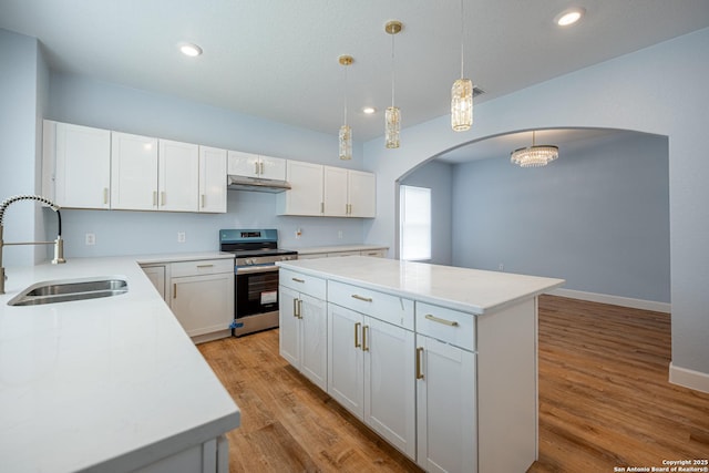 kitchen with arched walkways, stainless steel electric stove, a sink, and light wood-style flooring