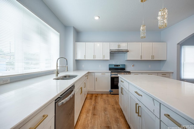 kitchen with a sink, light countertops, white cabinets, stainless steel appliances, and light wood-style flooring
