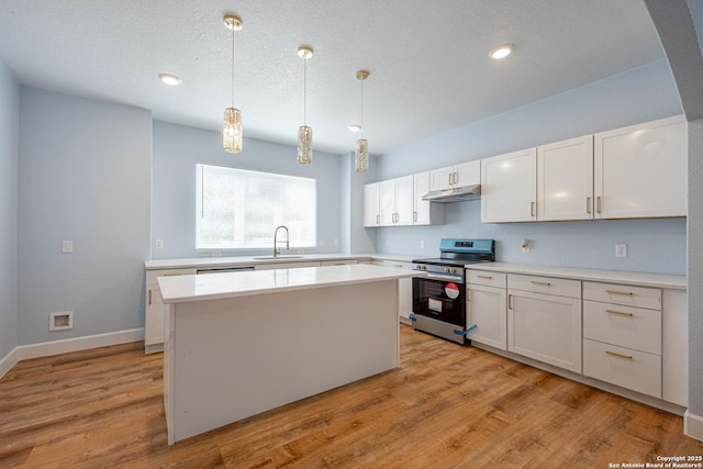 kitchen with electric range, a sink, light countertops, white cabinets, and under cabinet range hood